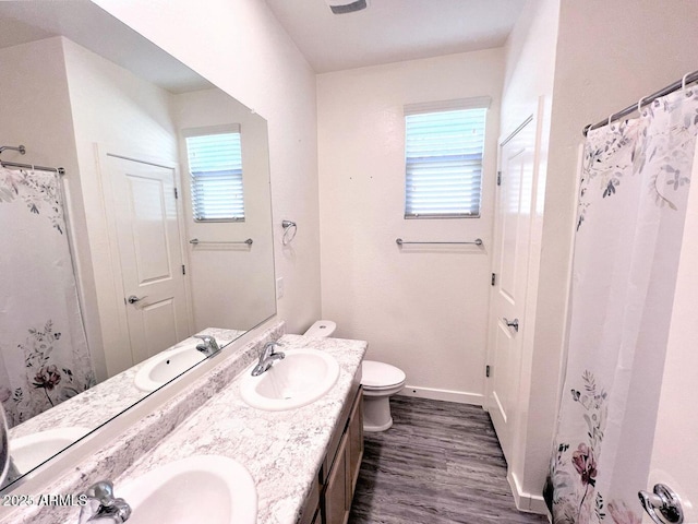 bathroom with toilet, double vanity, a sink, and wood finished floors