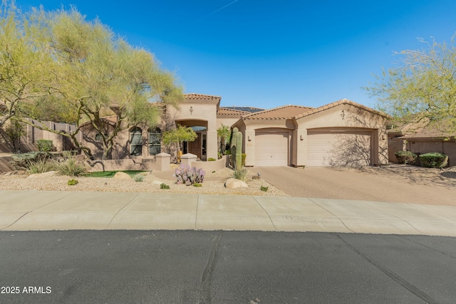 mediterranean / spanish-style home with decorative driveway, a tile roof, stucco siding, fence, and a garage