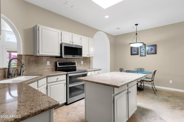 11775 E Becker Ln, Scottsdale, AZ 85259 - kitchen featuring stainless steel appliances, arched walkways, a sink, a center island, and white cabinetry