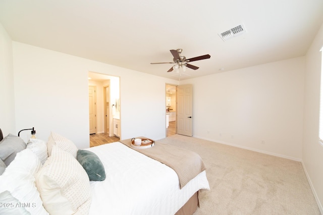 bedroom with ceiling fan, light colored carpet, and ensuite bathroom