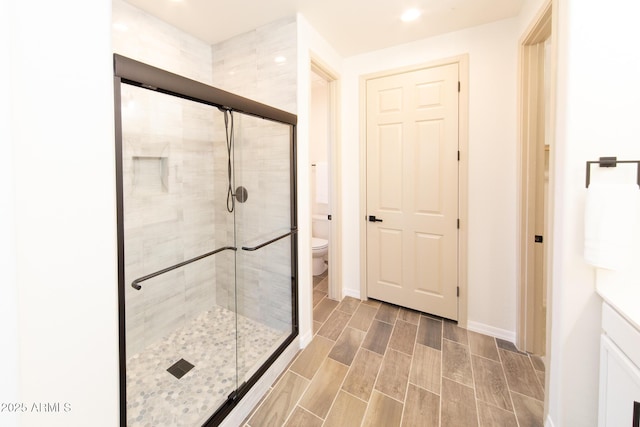 bathroom featuring a shower with shower door and toilet