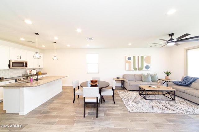 living room with sink, a wealth of natural light, and ceiling fan