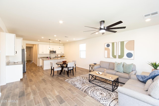 living room with light hardwood / wood-style flooring and ceiling fan