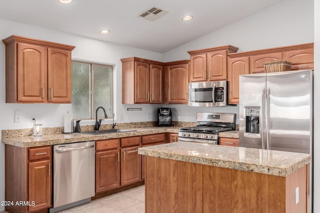 kitchen with stainless steel appliances, sink, light tile patterned floors, a center island, and lofted ceiling