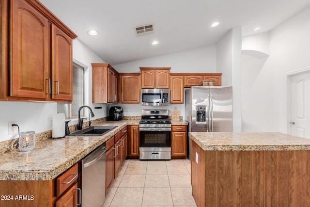 kitchen featuring a center island, lofted ceiling, sink, light tile patterned floors, and appliances with stainless steel finishes