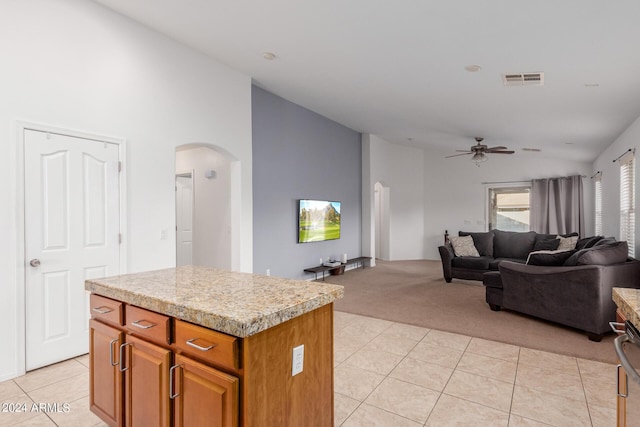 kitchen with ceiling fan, a kitchen island, light tile patterned floors, and lofted ceiling