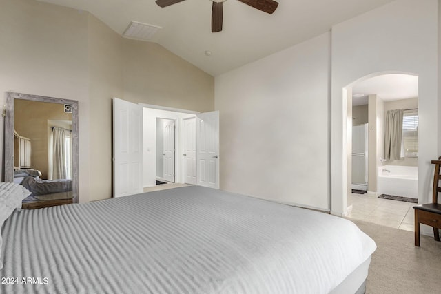 bedroom with ensuite bathroom, light tile patterned floors, ceiling fan, and vaulted ceiling