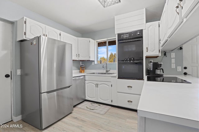 kitchen with sink, light hardwood / wood-style flooring, white cabinetry, and black appliances