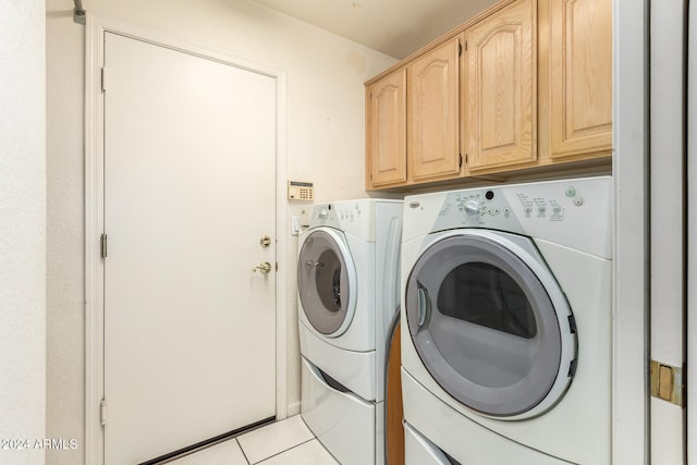 washroom featuring washer and clothes dryer, cabinets, and light tile patterned floors