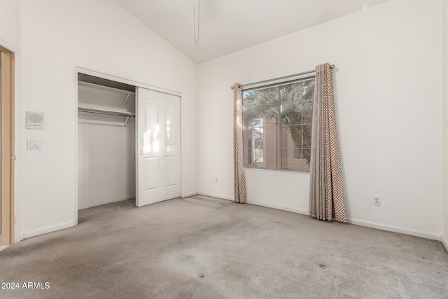 unfurnished bedroom featuring light colored carpet, vaulted ceiling, and a closet