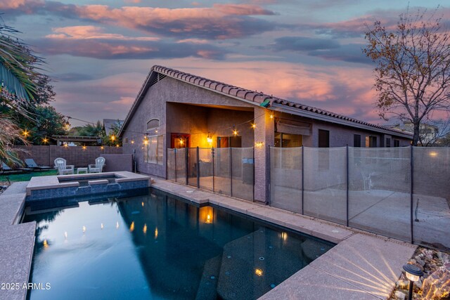 back house at dusk featuring a yard and covered porch