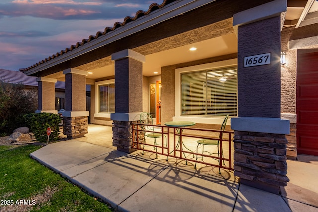 patio terrace at dusk featuring a porch