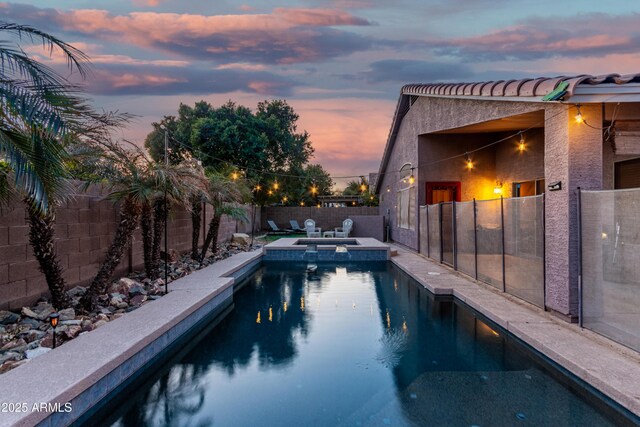 back house at dusk with a porch, a garage, and a yard