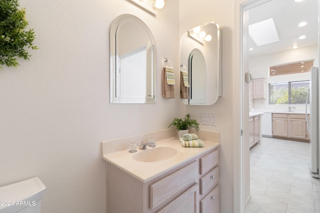 bathroom featuring toilet, vanity, and a skylight