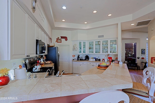 kitchen featuring white cabinets, stainless steel appliances, sink, kitchen peninsula, and a breakfast bar area