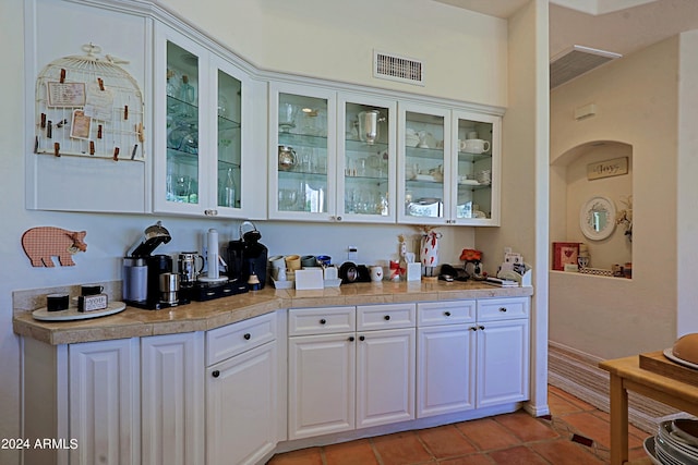 bar with light tile patterned floors and white cabinets