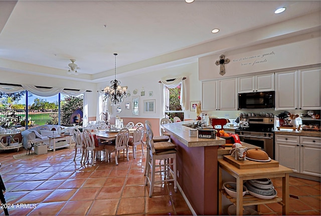 kitchen featuring stainless steel range, hanging light fixtures, white cabinets, and light tile patterned flooring