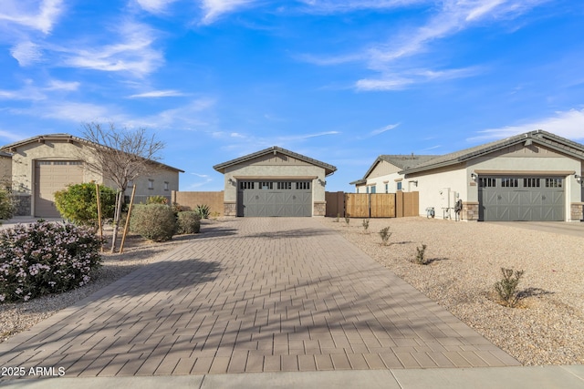 ranch-style house with stone siding, decorative driveway, fence, and stucco siding