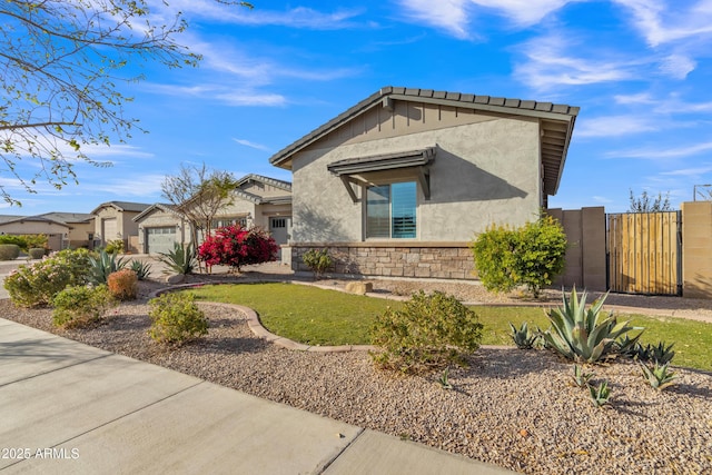 view of front facade featuring stone siding, a gate, and stucco siding