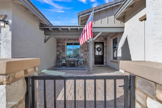 entrance to property featuring stone siding, covered porch, and stucco siding