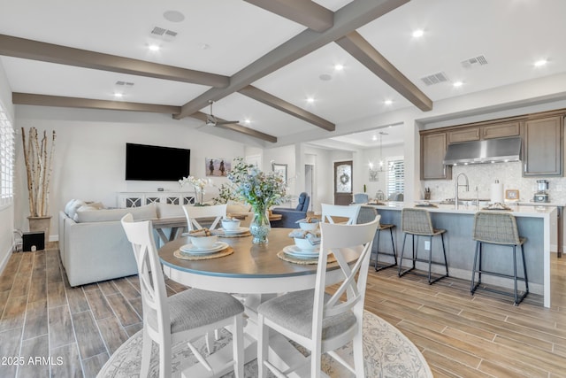 dining area featuring wood finish floors, visible vents, and lofted ceiling with beams