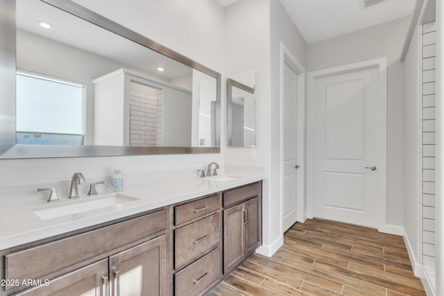 full bathroom featuring double vanity, baseboards, a sink, and wood finish floors