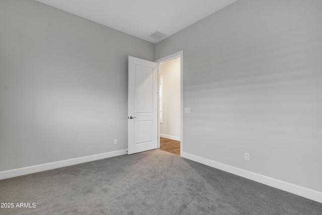 carpeted spare room featuring baseboards and visible vents