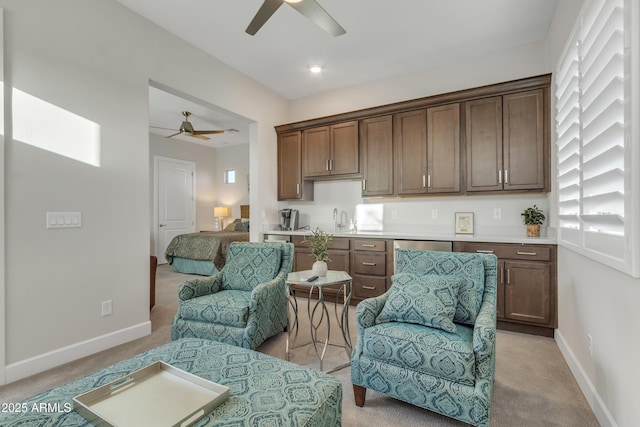 sitting room with light colored carpet, a ceiling fan, and baseboards