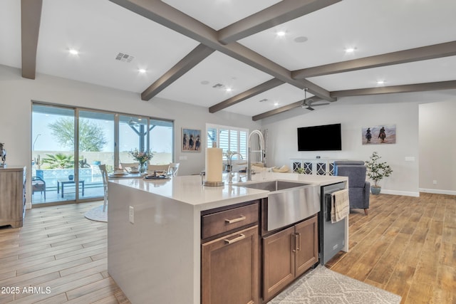 kitchen with light wood finished floors, light countertops, visible vents, stainless steel dishwasher, and a sink