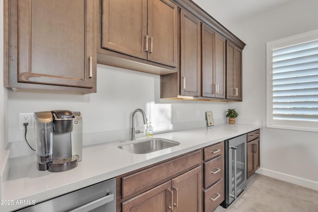 kitchen featuring wine cooler, a sink, baseboards, light countertops, and stainless steel dishwasher