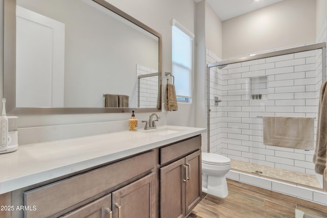 bathroom with wood finished floors, a shower stall, toilet, and vanity