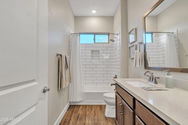 bathroom with toilet, wood finished floors, vanity, baseboards, and shower / bath combo with shower curtain