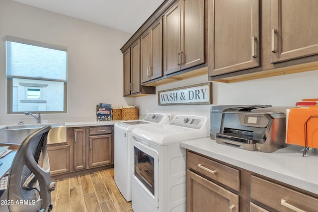 laundry room featuring cabinet space, wood tiled floor, a sink, and washing machine and clothes dryer