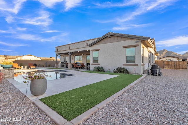 rear view of house with a fenced backyard, an outdoor kitchen, a patio, and stucco siding