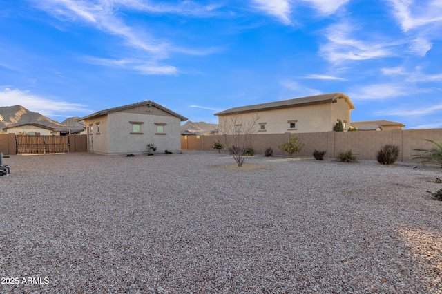 rear view of house with a fenced backyard, a gate, and stucco siding