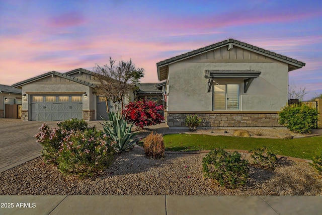 view of front of property featuring stone siding, decorative driveway, an attached garage, and stucco siding