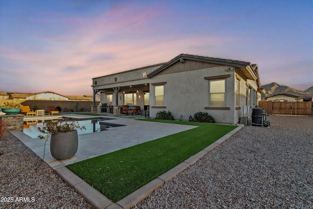 back of house featuring a patio, an outdoor kitchen, a fenced backyard, a fenced in pool, and stucco siding