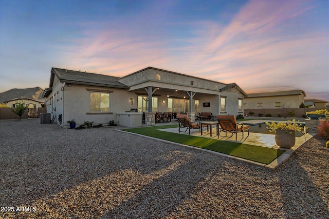 rear view of house with stucco siding, fence, central AC, and a patio