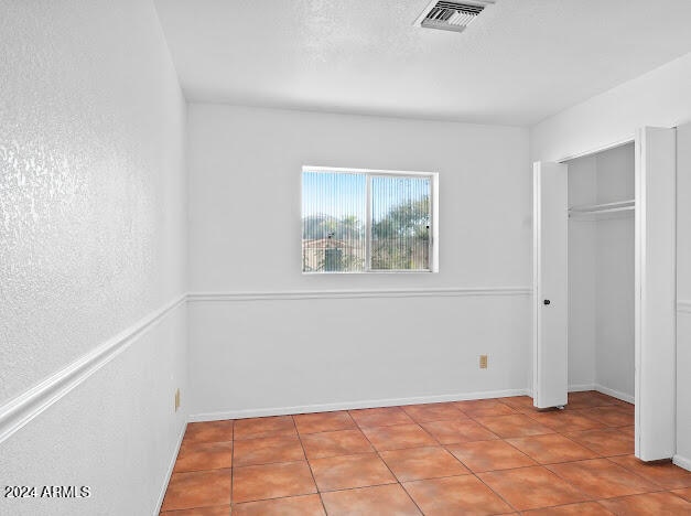 unfurnished bedroom with a closet and tile patterned flooring