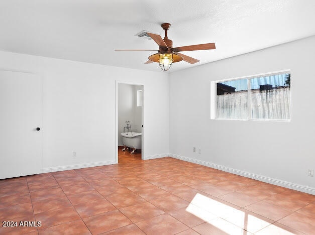 unfurnished bedroom with light tile patterned floors, ceiling fan, and ensuite bath