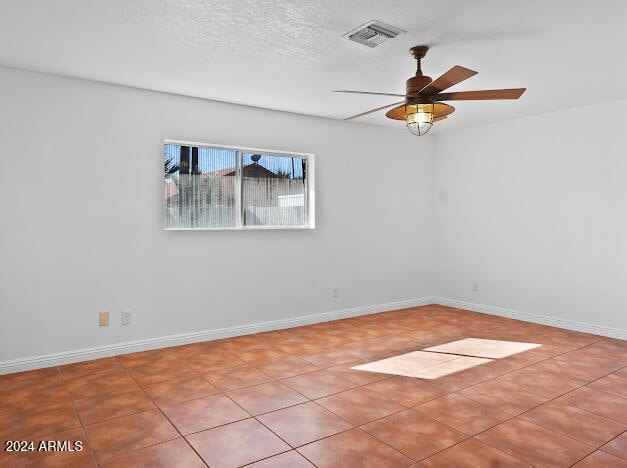 unfurnished room with a textured ceiling, ceiling fan, and light tile patterned floors