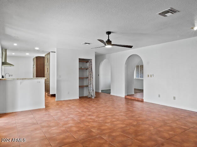 unfurnished living room featuring a textured ceiling, ceiling fan, and sink