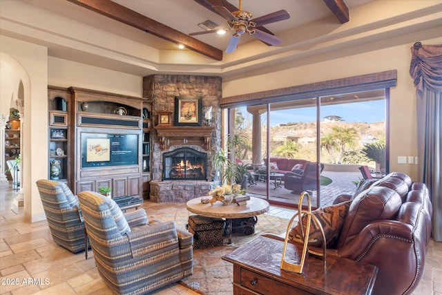 15956 E Tombstone Trl, Fountain Hills, AZ 85268 - living room with beamed ceiling, stone tile flooring, a fireplace, arched walkways, and a ceiling fan