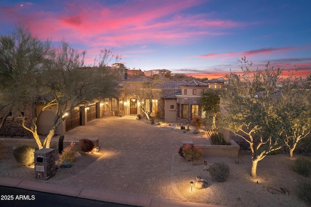 view of front of home featuring stucco siding, a tiled roof, decorative driveway, and a garage