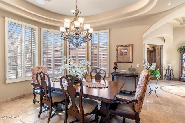 15956 E Tombstone Trl, Fountain Hills, AZ 85268 - dining space with baseboards, a tray ceiling, a wealth of natural light, an inviting chandelier, and stone tile flooring