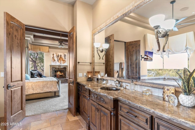 15956 E Tombstone Trl, Fountain Hills, AZ 85268 - bathroom with vanity, a warm lit fireplace, a ceiling fan, and ensuite bathroom