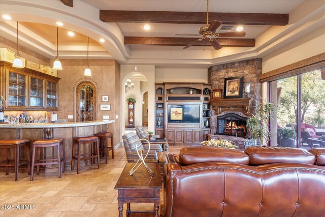 15956 E Tombstone Trl, Fountain Hills, AZ 85268 - living area with beam ceiling, stone tile floors, arched walkways, a fireplace, and ceiling fan