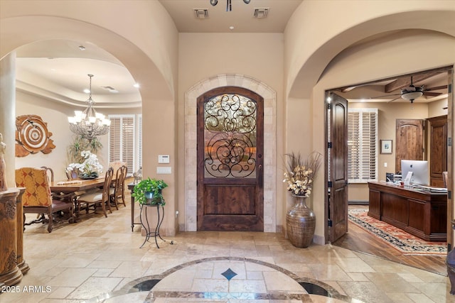 15956 E Tombstone Trl, Fountain Hills, AZ 85268 - entryway with ceiling fan with notable chandelier, stone tile floors, visible vents, and arched walkways