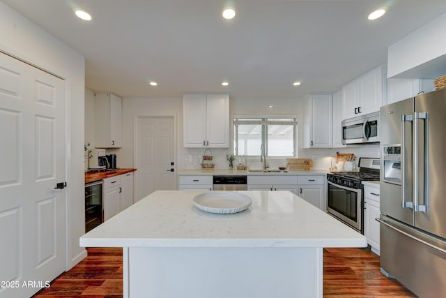 kitchen with beverage cooler, appliances with stainless steel finishes, dark wood-style flooring, a sink, and recessed lighting