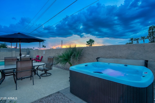 4008 N 85th St, Scottsdale, AZ 85251 - patio terrace at dusk featuring a hot tub, a fenced backyard, outdoor dining space, and a patio area